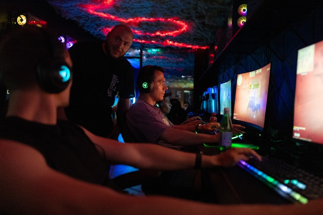 Gamers playing video games together in a dark room with glowing screens.