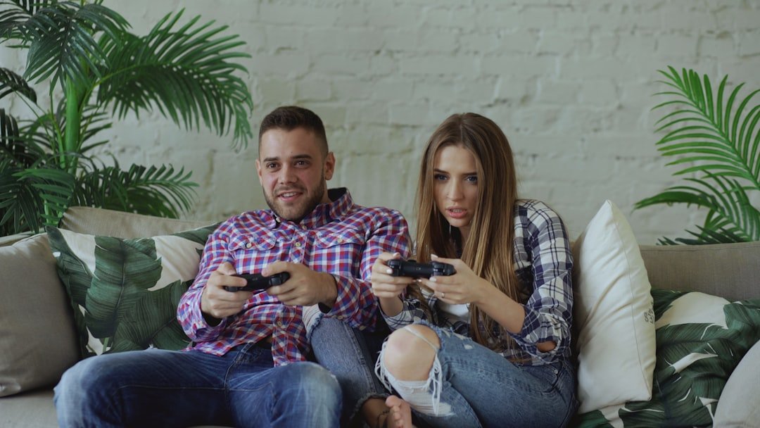Couple sitting on sofa playing video games together