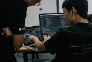 Two men working on computers at desks in an office setting