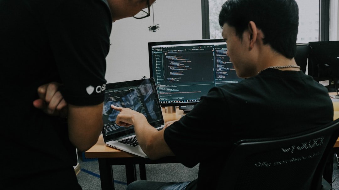 Two men working on computers at desks in an office setting