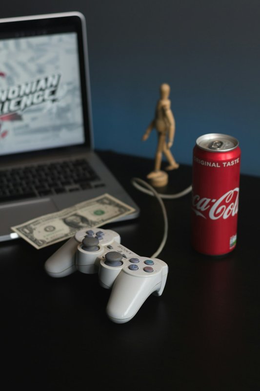 White PlayStation 4 controller next to Coca-Cola can on surface